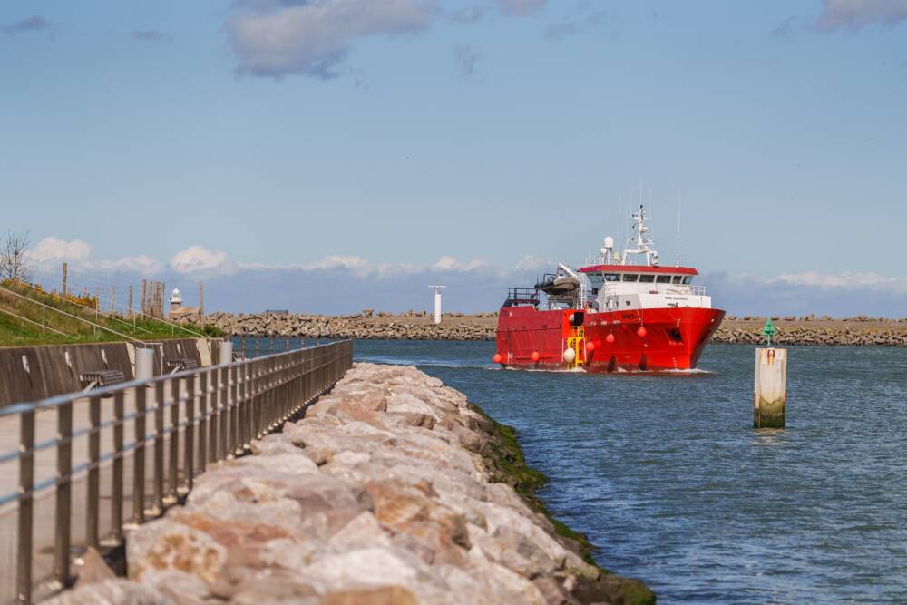 Photo de l'embouchure du port de Calais où entre un bateau de pêche le long de la promenade du Perré Risban.