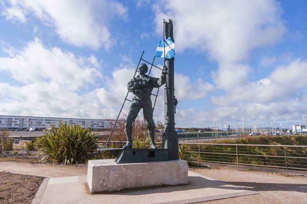 Photo de la Statue à l'effigie du corsaire Tom Souville et le pavillon bleu et blanc de la Cité portuaire e Calais.