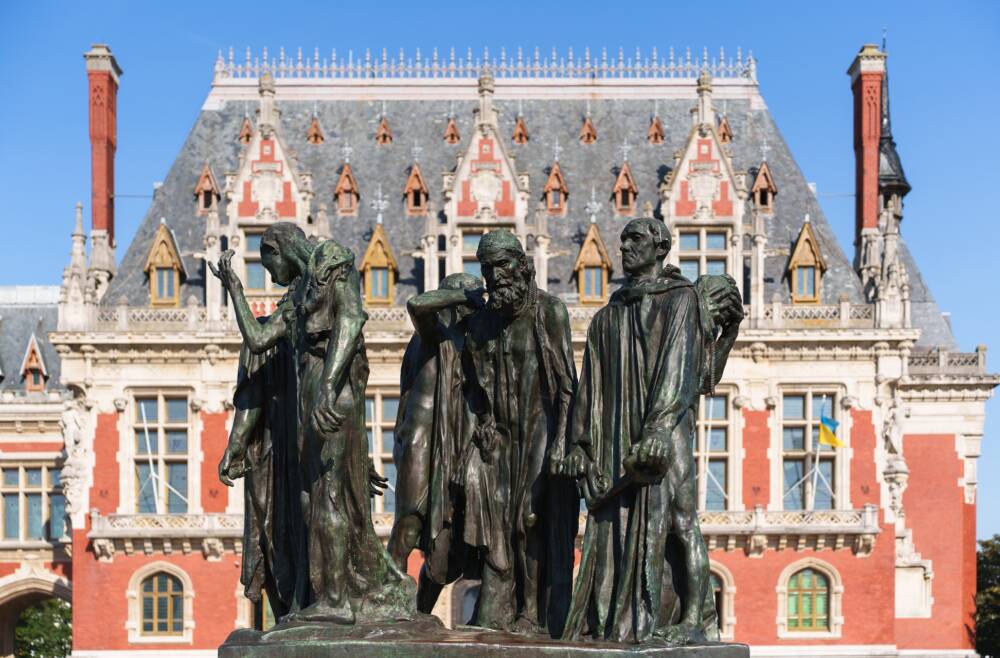 Groupe Statutaire d'Auguste Rodin : les Bourgeois de Calais faisant face à l'Hôtel de ville de Calais et son beffroi.