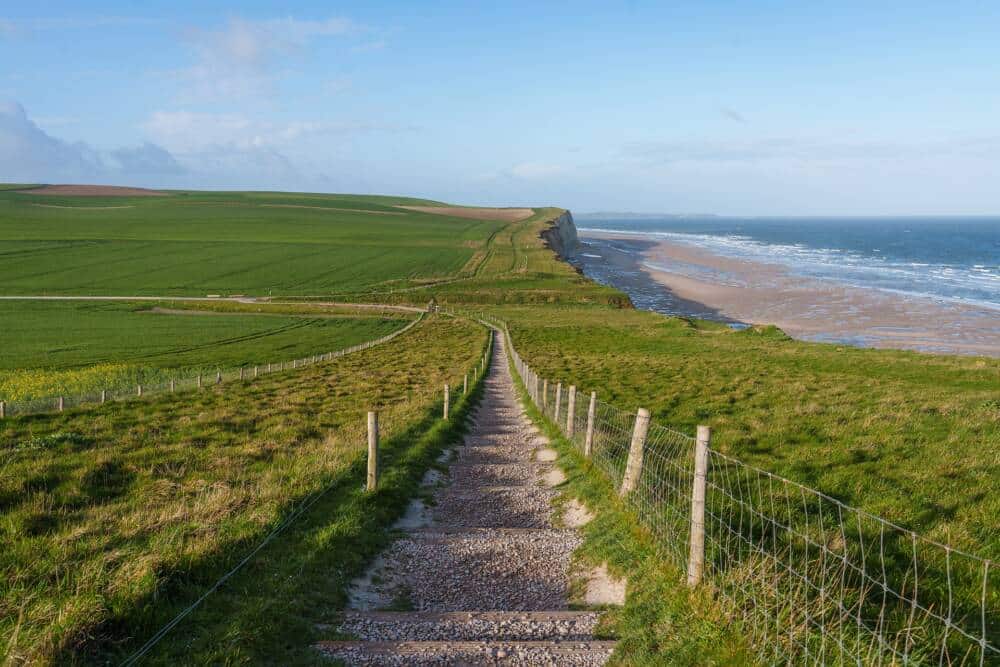 Vue des sentiers balisés du Cap Blanc-Nez avec la mer et le littoral sur le flanc droit et les prairies sur la gauche.