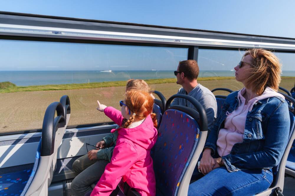 Une famille contemple la mer à l'horizon lors d'une escapade à bord de la Div'in, bus à impériale.