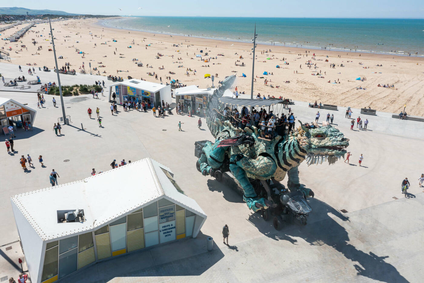 Le Dragon de Calais, animal mécanique colossal qui évolue sur le front de mer rénové de Calais et sa plage de sable fin en arrière plan.