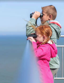 Une famille sur le belvédère du cap Blanc-Nez équipée de jumelles pour observer le panorama.