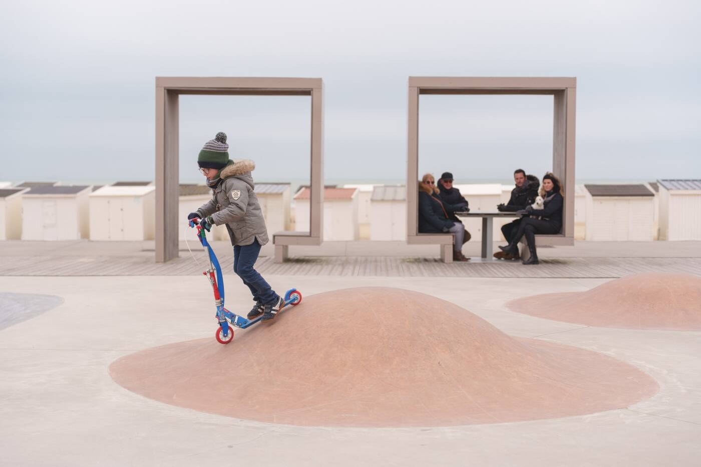 Glisse hivernale d'une jeune homme bien emmitouflé sous son bonnet à trottinette dans le skatepark de Calais