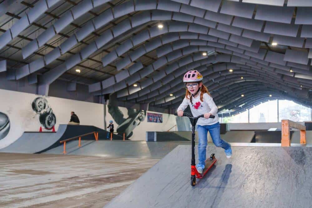 Une jeune fille déjà grande qui pratique la glisse sur trottinette au skatepark Zap'Ados de Calais