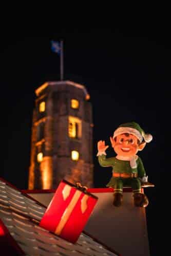 La Tour du Guet de Calais de nuit avec les décors de Noël au premier plan qui habillent le marché de Noël.