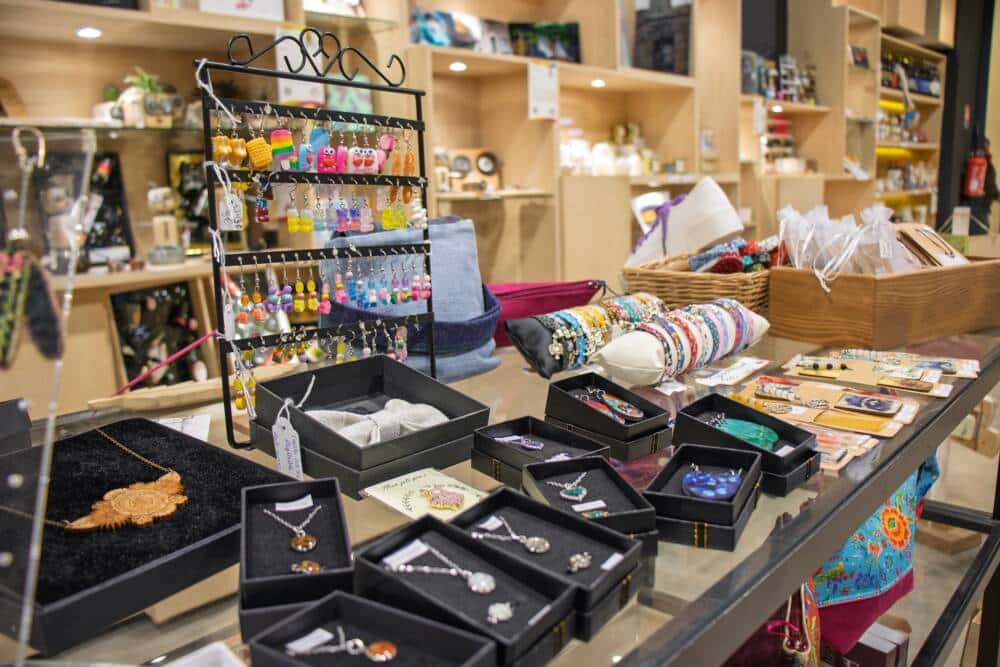 Assortiment de produits artisanaux au Comptoir de l’Îlot à Calais, incluant bijoux faits main, porte-clés colorés, bracelets uniques et accessoires locaux. Une vitrine créative idéale pour des cadeaux authentiques et originaux à Noël, valorisant le savoir-faire des créateurs de la région.