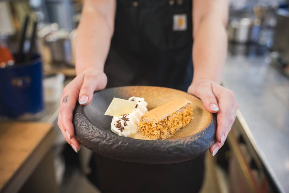 Dessert “Le Calais”, spécialité locale revisitée par le restaurant L’Aquar’aile à Calais. Présenté sur une assiette artisanale, composée d’un biscuit Progrès, d’une crème au café et à la chicorée, et d’un glaçage au fondant aromatisé au café.