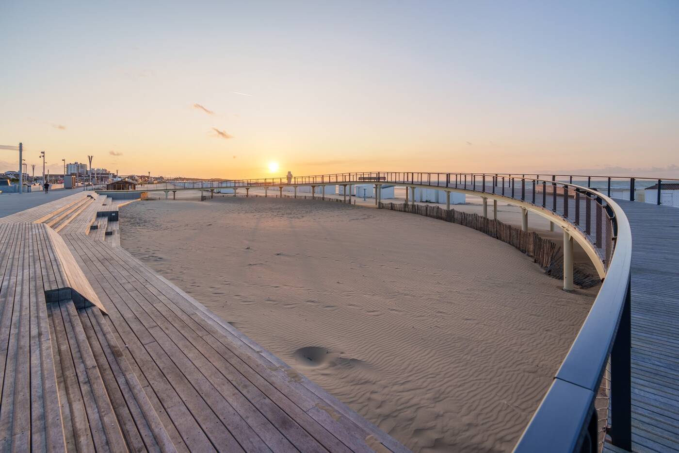 Le belvédère surplombant la plage de Calais au coucher du soleil, offrant une vue panoramique sur le sable et l’horizon. Sa structure moderne en bois et métal invite à la promenade et à la contemplation dans une atmosphère paisible et lumineuse, emblématique du front de mer de Calais.