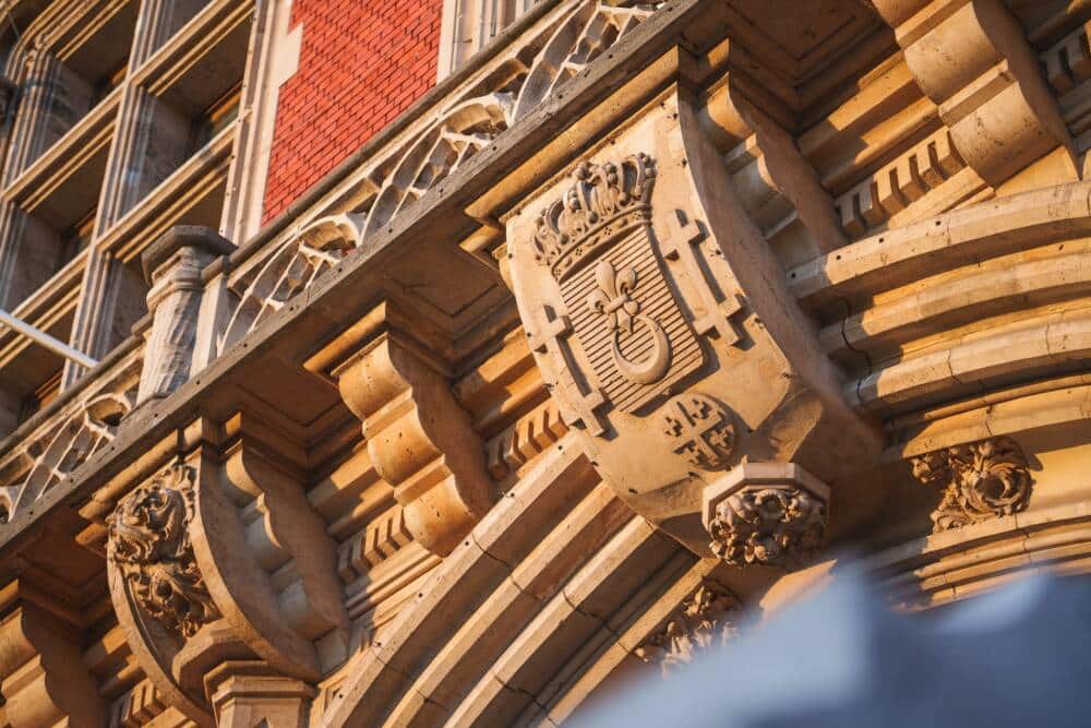 Le blason sculpté de la ville de Calais ornant la façade de l’Hôtel de Ville, symbole historique marqué par la fleur de lys et la couronne royale.