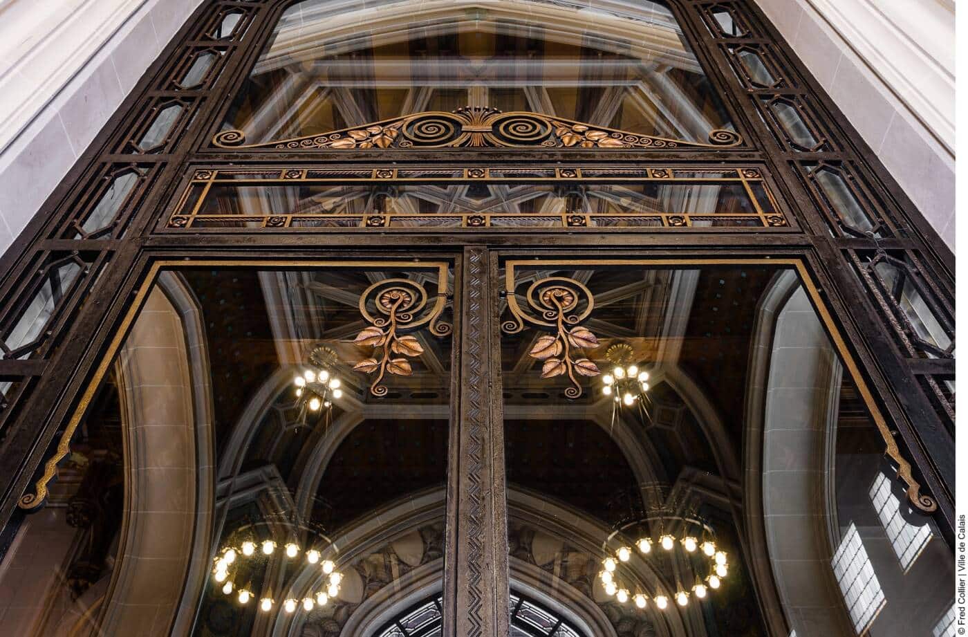 Détail des ferronneries de l’Hôtel de Ville de Calais, réalisées par Adalbert Szabo. Un travail d’orfèvre mêlant arabesques et motifs floraux, capturant l’élégance de l’architecture néo-flamande de ce monument emblématique classé au patrimoine mondial de l’UNESCO.