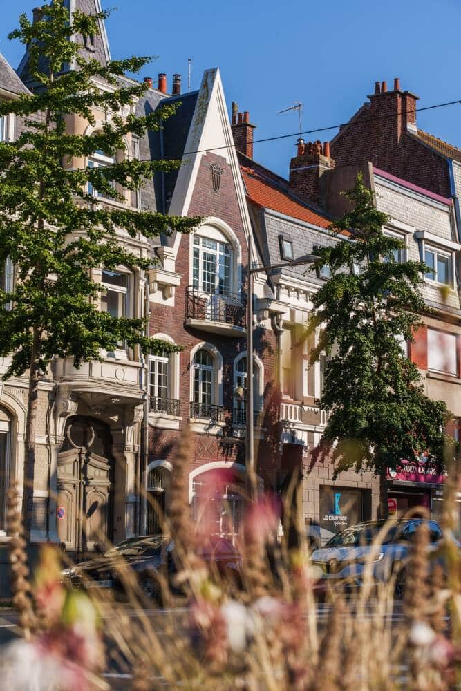 Une vue des façades emblématiques de Calais, mélangeant architecture Art déco et styles traditionnels, sous un ciel bleu.