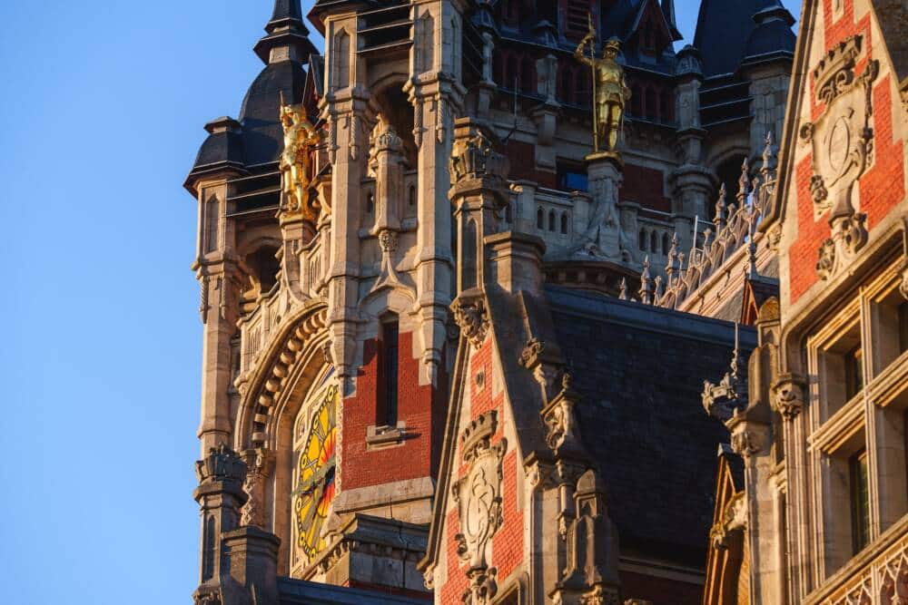 La façade de l’Hôtel de Ville de Calais, mettant en valeur son architecture remarquable, son horloge emblématique et ses statues dorées sous une belle lumière.